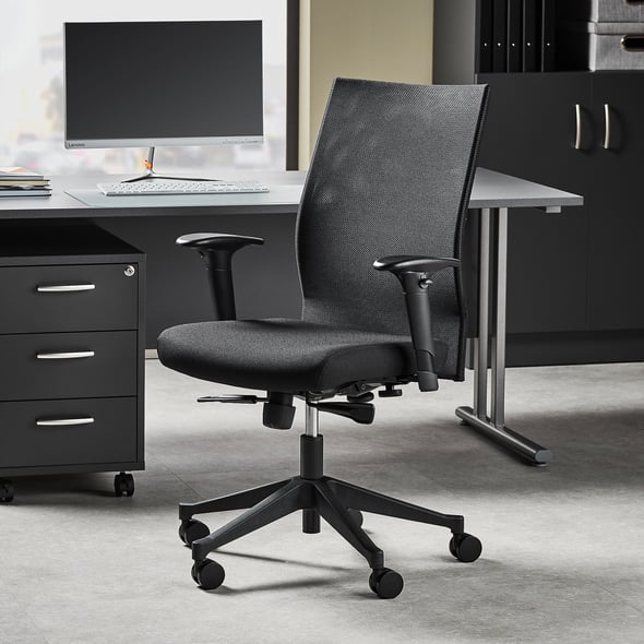 A sleek and professional office setup featuring a black ergonomic office chair with adjustable armrests and a high backrest, placed on castors for mobility. The workspace includes a modern desk with a computer monitor and a keyboard, along with a black drawer unit and storage cabinets, creating a tidy and functional environment.