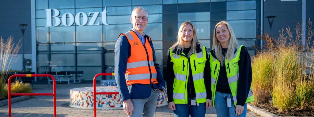 Three colleagues wearing hi-vis vests standing outside of Boozt headquarters