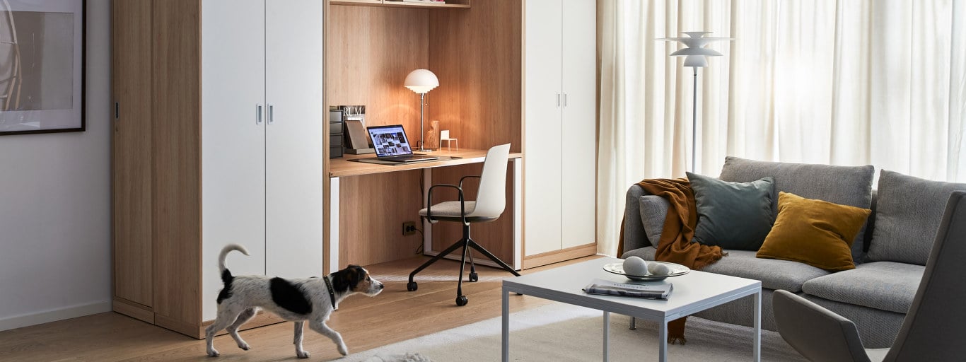 En hjemmearbejdsplads indrettet i en stue mellem skabe