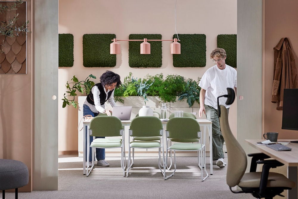 modern and cosy meeting space with a clean, stylish look. One person is bent over near the table and another one is standing and looking toward the room