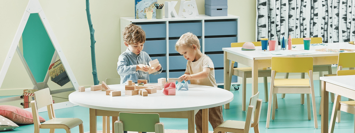 children playing around a round table in a classroom