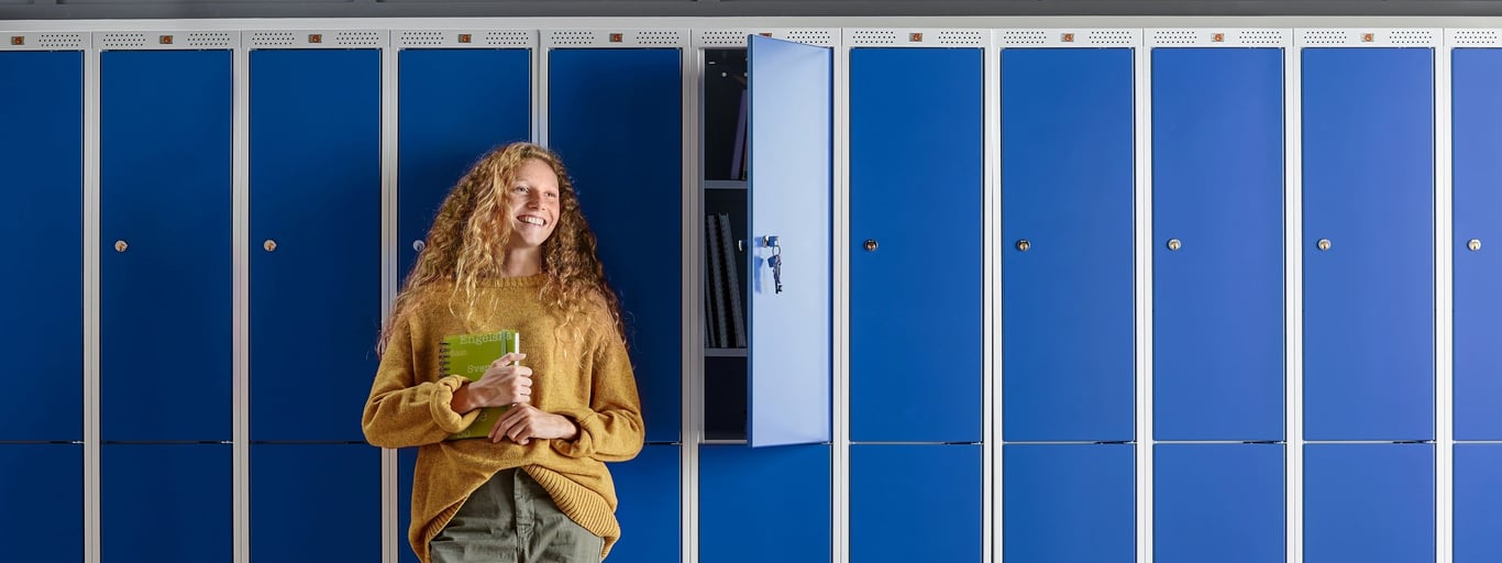 a smiling young student by the school lockers