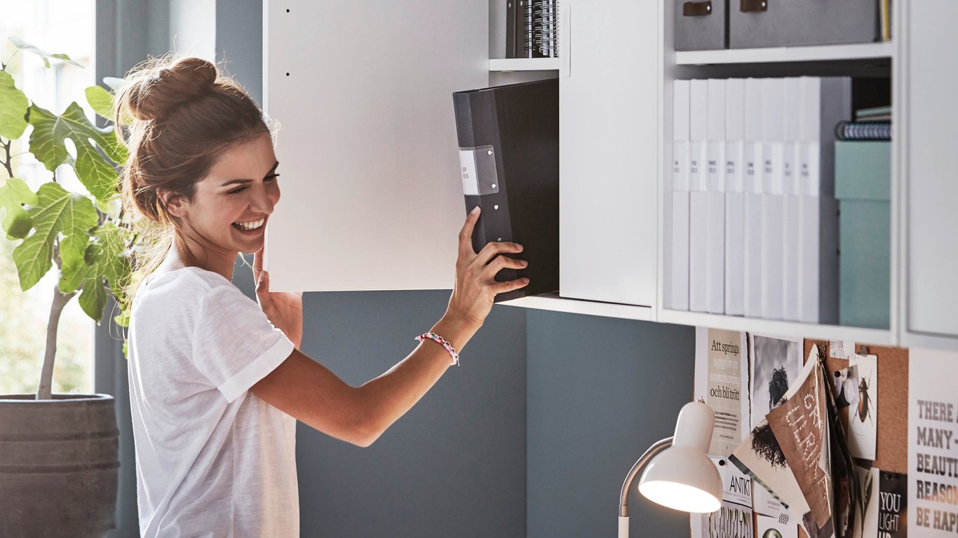 Frau nimmt einen Ordner aus einem Schrank