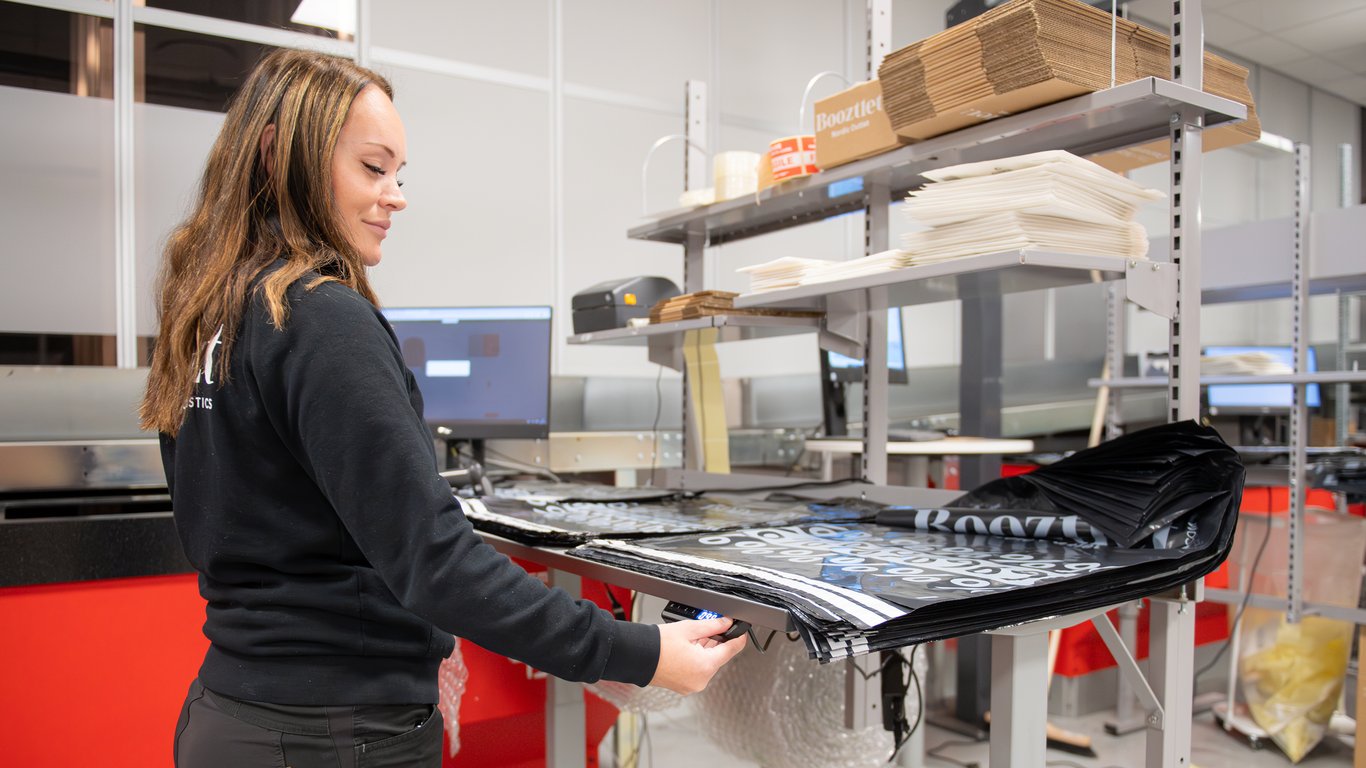 En ansat hos Boozt arbejder ved et pakkebord