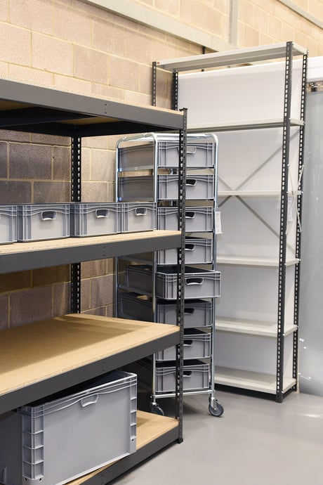 Industrial warehouse shelving units and plastic tote storage boxes on a mobile trolley at the AJ Products showroom in Farnborough