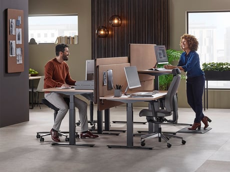 Two work colleagues smiling and engaged on a discussion while reviewing documents on their computer