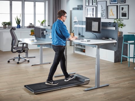 a person walking on a treadmill while working at his desk