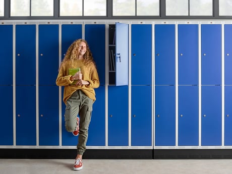 a smiling young student by the school lockers 