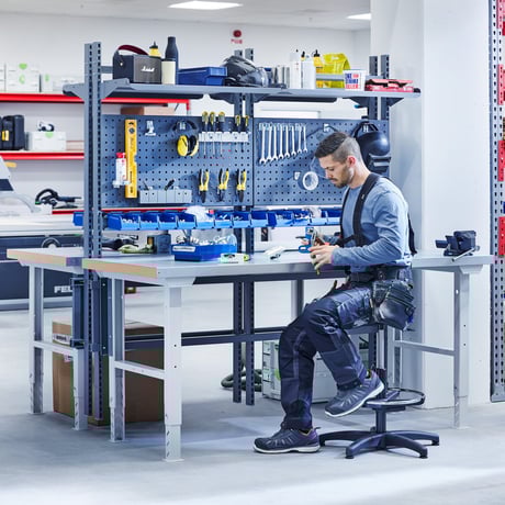A man is seated on a stool in a workshop