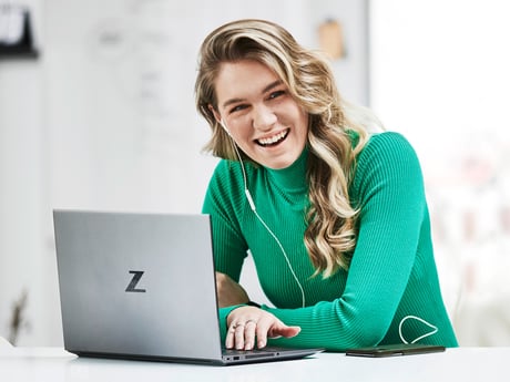 a young person smiling while working with her laptop