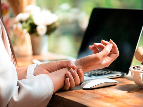 a lady holding her wrist in pain due to mouse arm