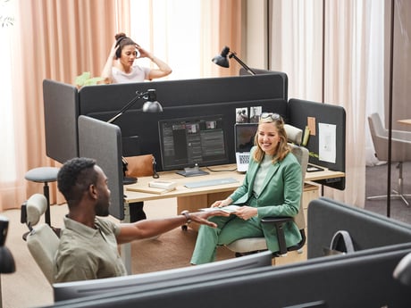 Colleagues chatting in office with ergonomic furniture and sound absorbing screens