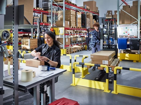 Eine Frau arbeitet an einem Verpackungstisch in einem Lager