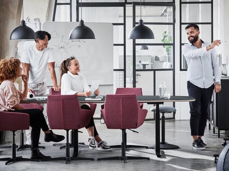 Collega's aan een vergadertafel met paarse stoelen