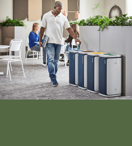 Man throwing rubbish in a recycling bin in an office cafeteria