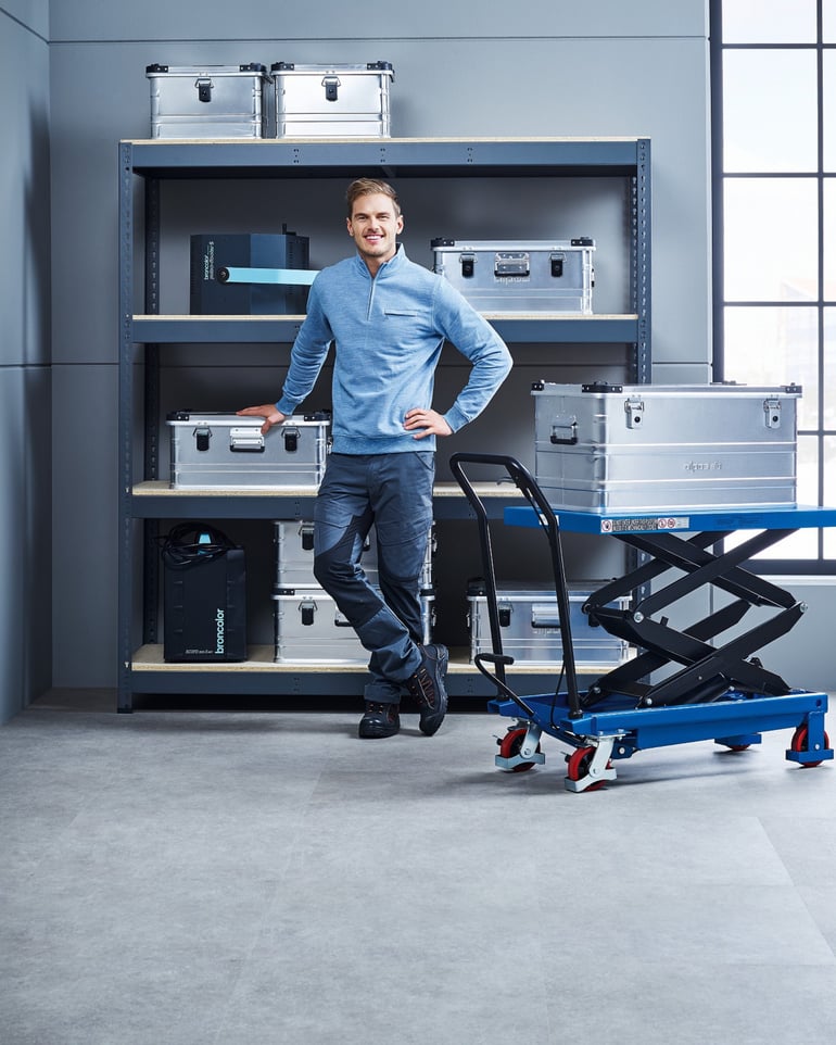 Muž ve skladu s regálem a zvedacím stolem