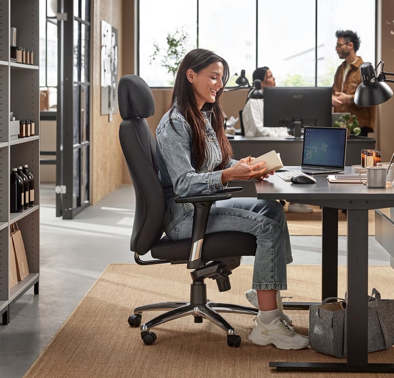 A woman is sitting at a desk in an office by AJ Products