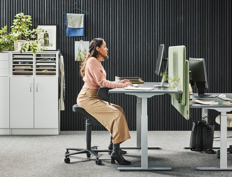 lady working at her desk sitting on a Saddle chair EPSOM with backrest and rocking mechanism