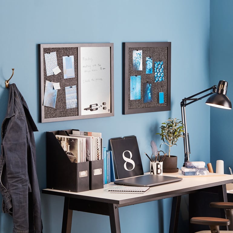 Two sleek, textured bulletin boards over a desk against a blue wall