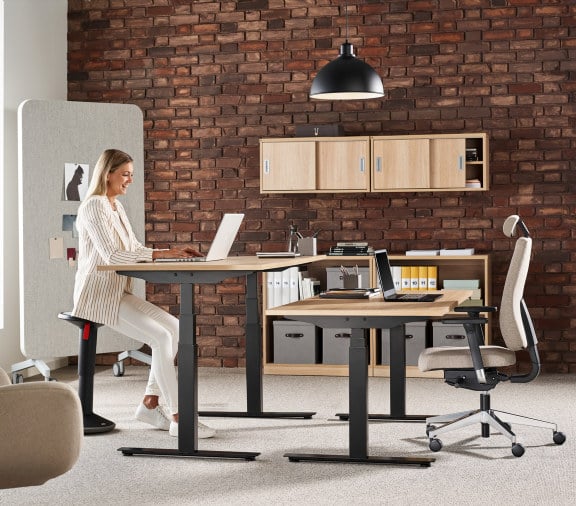 a person sitting at a height-adjustable desk in a dark office