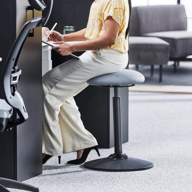 a woman sitting on an active sitting balance stool in an office