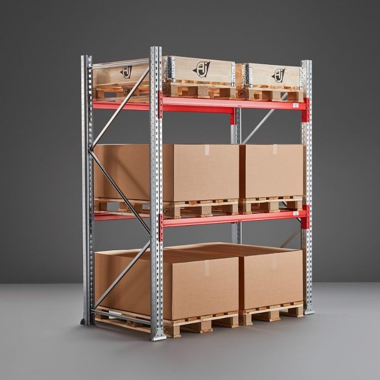 Three-tiered pallet racking system. Heavy-duty, industrial-style racking system with red support beams and galvanized steel uprights. The industrial shelving stores pallets directly on the shelves.
