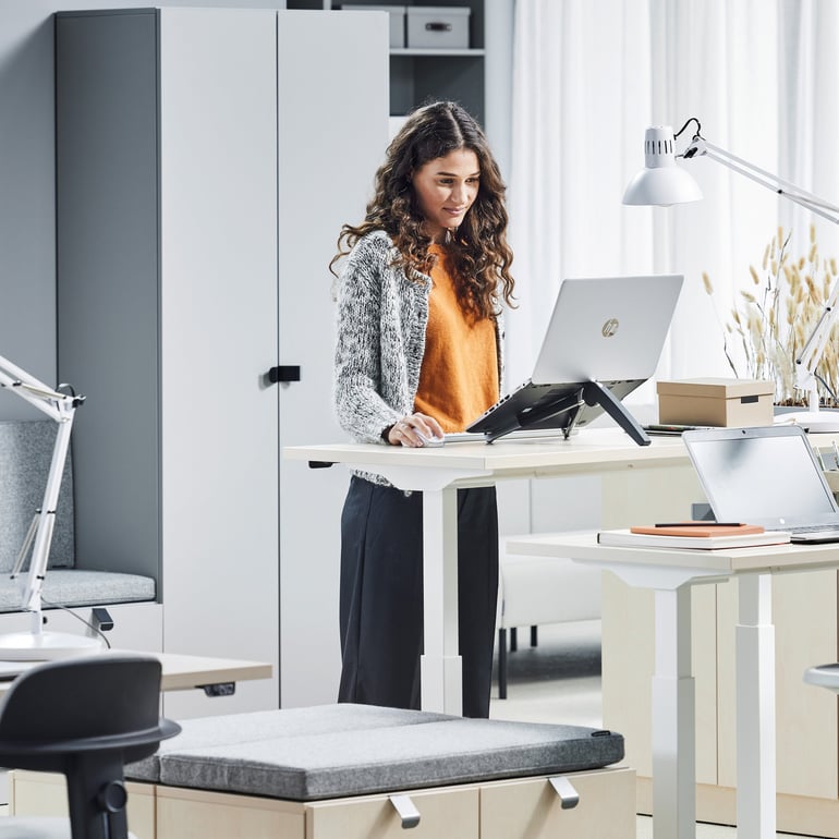 Woman standing and working at a height-adjustable desk