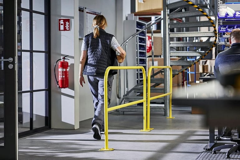 a warehouse worker walking beside a safety barrier