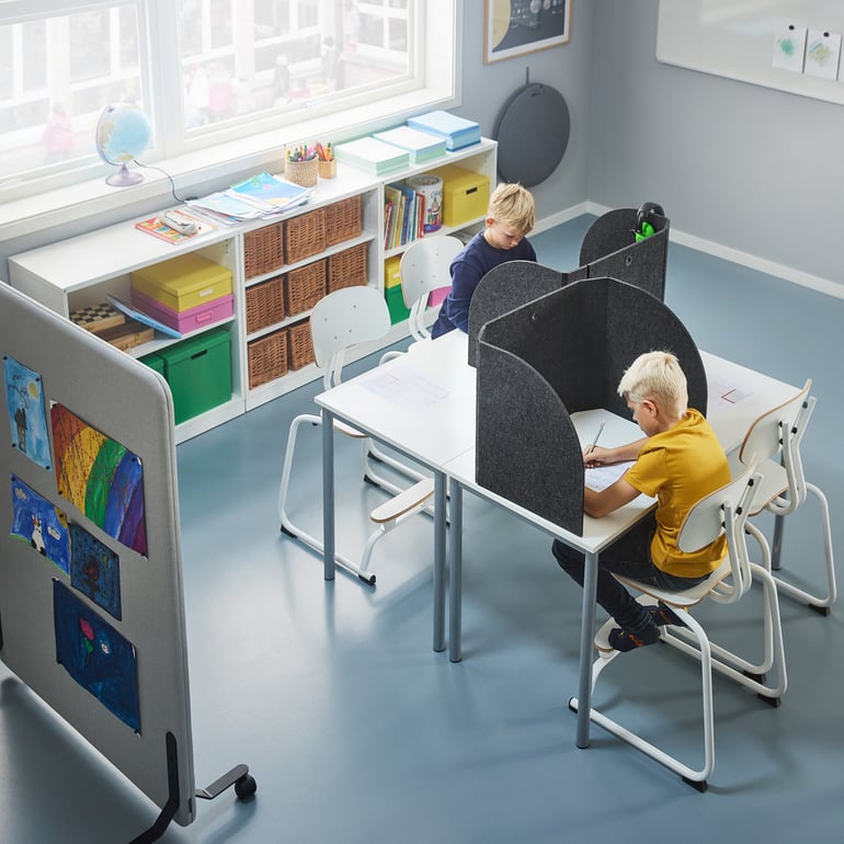 To drenge koncentrerer sig ved skoleborde med bordskærme