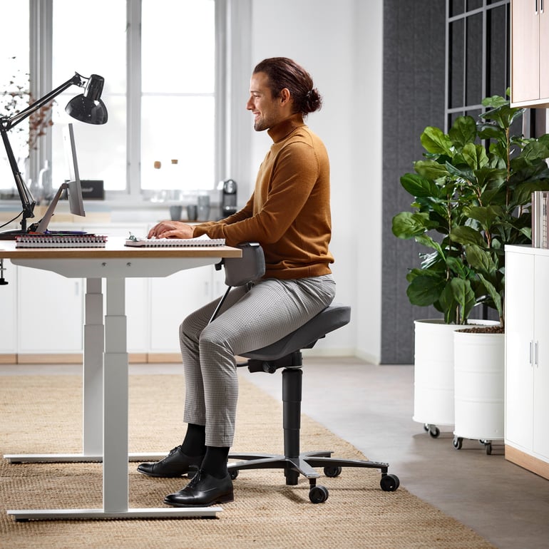 Mand der sidder ved et skrivebord på en ergonomisk stol