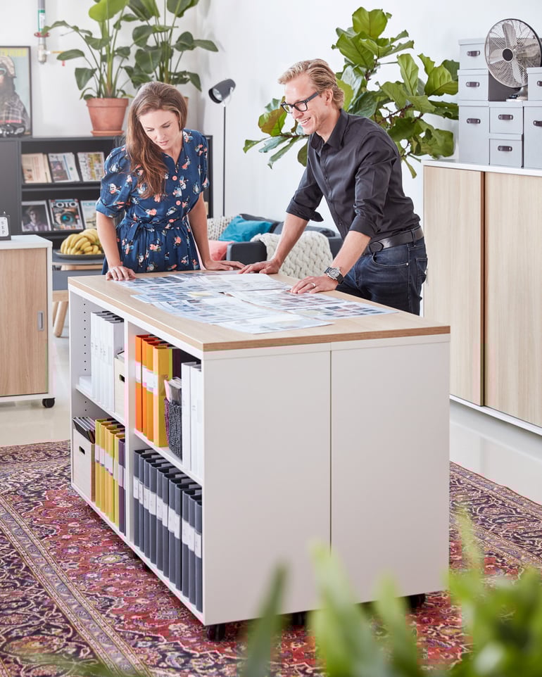 Ein Büro mit zwei Personen, die auf einer Arbeitsinsel Dokumente studieren
