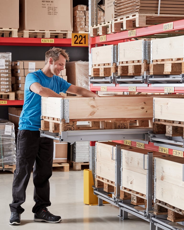 En lagerarbeider bruker en uttrekksenhet på et pallereol