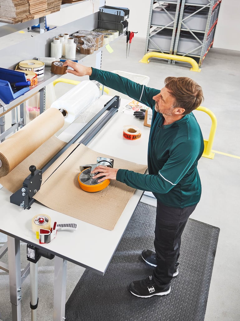 Man som sträcker sig till hyllan som sitter på arbetsbänken