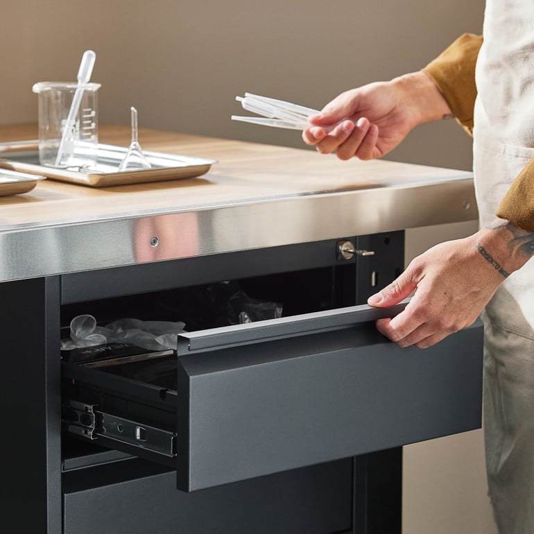 En person som drar ut en låda som tillhör arbetsbänken