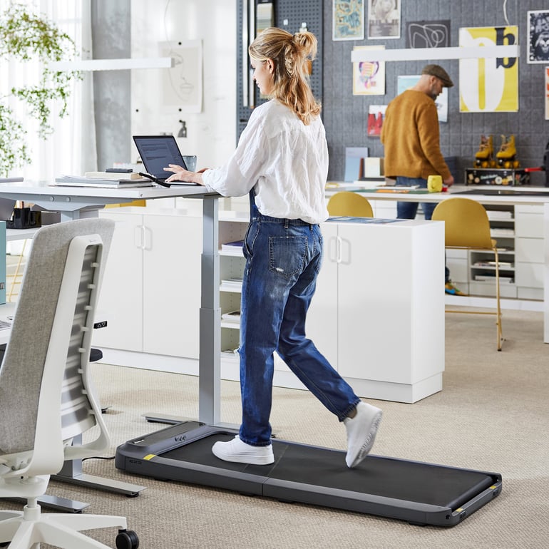 Woman walking on a treadmill while working at a desk