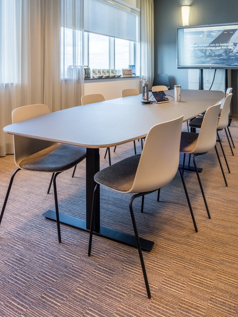 Vergaderruimte met zit-sta vergadertafel en stapelbare vergaderstoelen