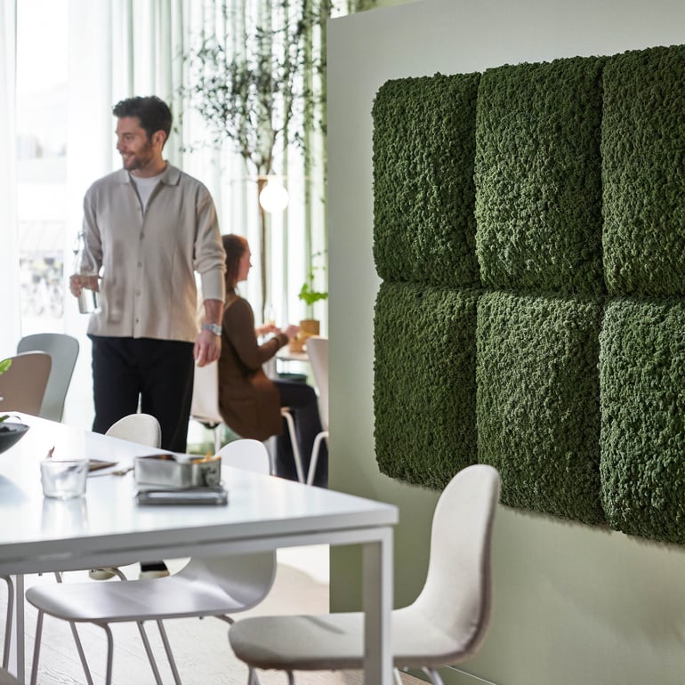 image of a section of a canteen with wall sound absorber panels and white furniture