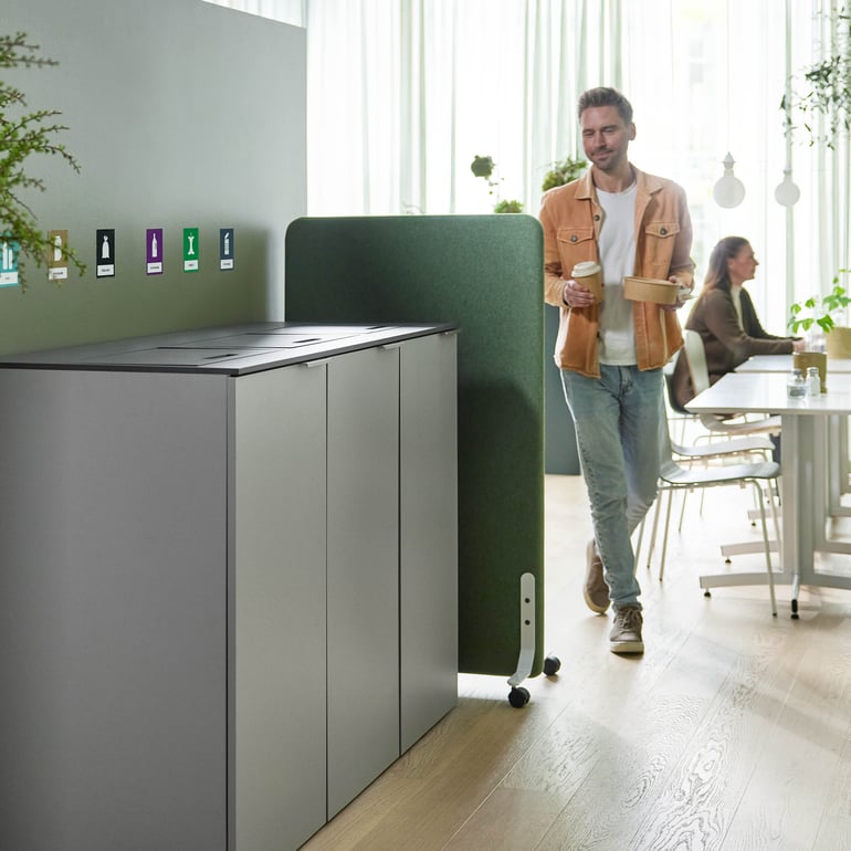 a staff member at the canteen walking towards the waste sorting unit