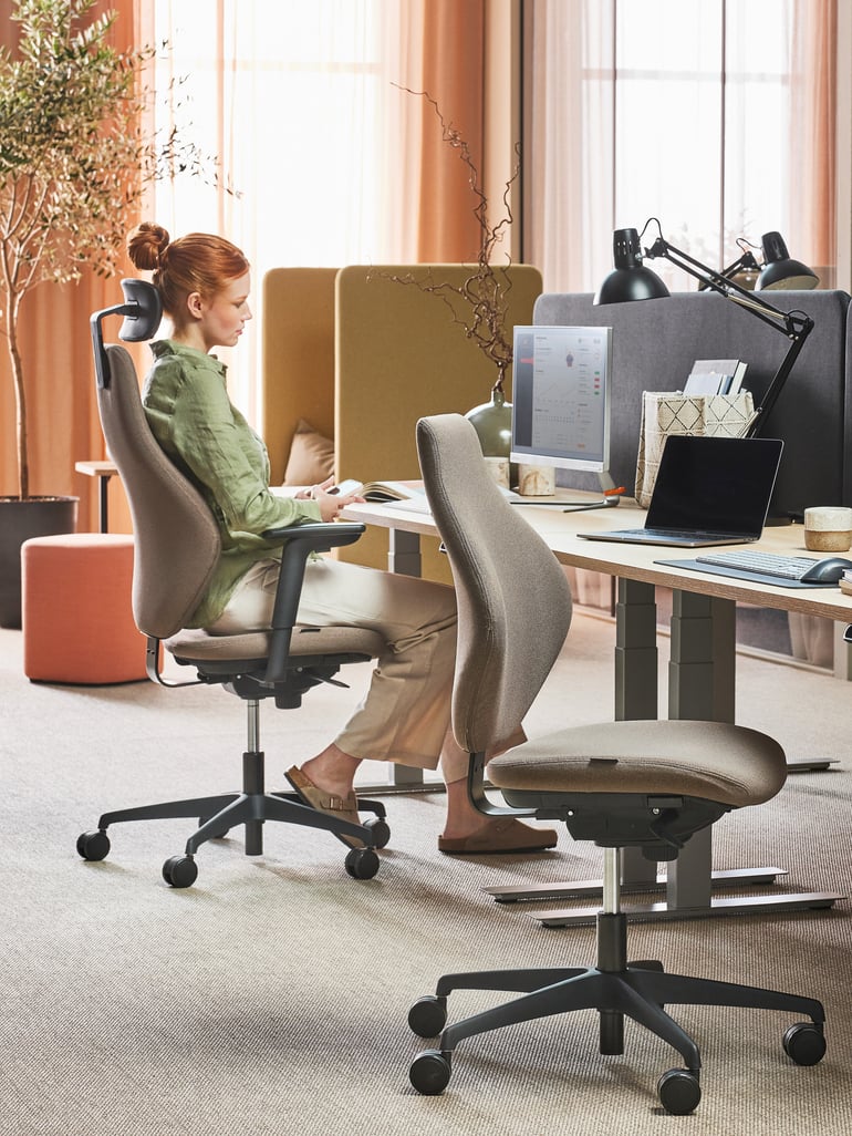 A lady sitting at a height-adjustable desk and working on a computer.