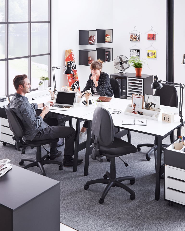 Twee mensen zitten ontspannen aan hun bureau in een kantoor