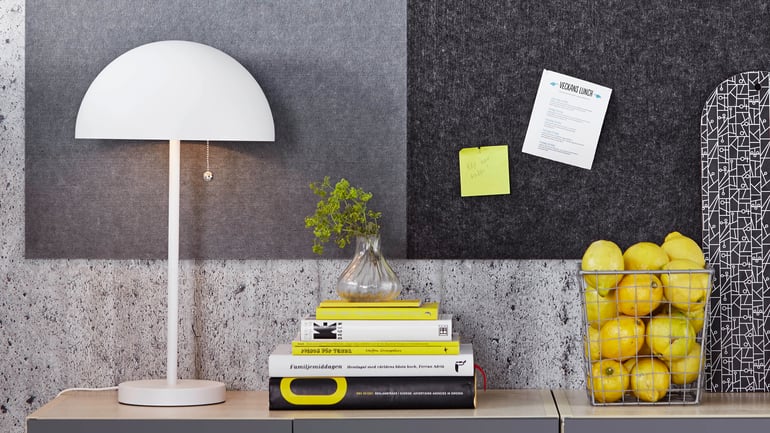 A lamp, books and lemons in a basket on a table