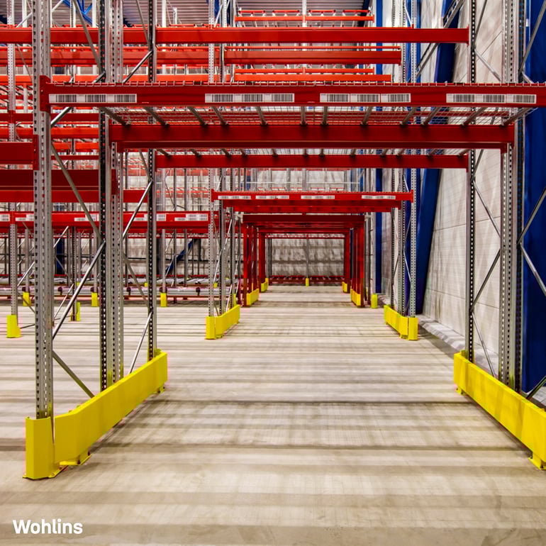 Interior of a large warehouse with bright red and yellow shelves stocked with goods
