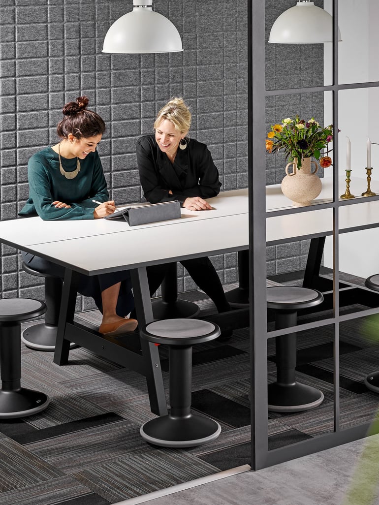 Zwe Kolleginnen sitzen am Tisch im Büro und führen ein Gespräch