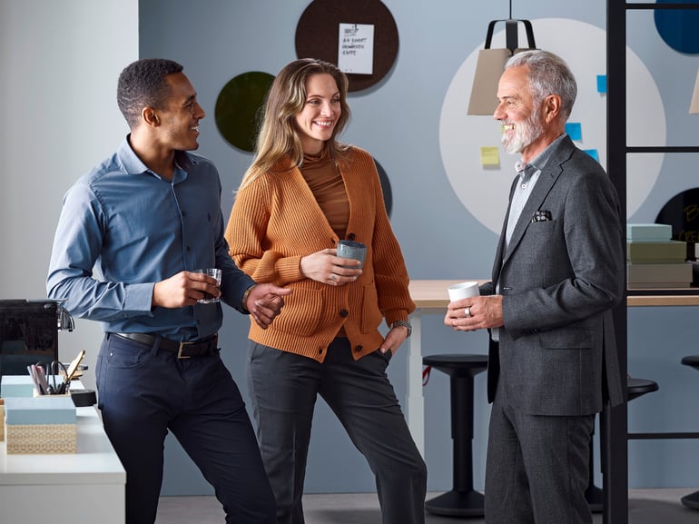 Drei Kollegen trinken Kaffee und unterhalten sich im Büro