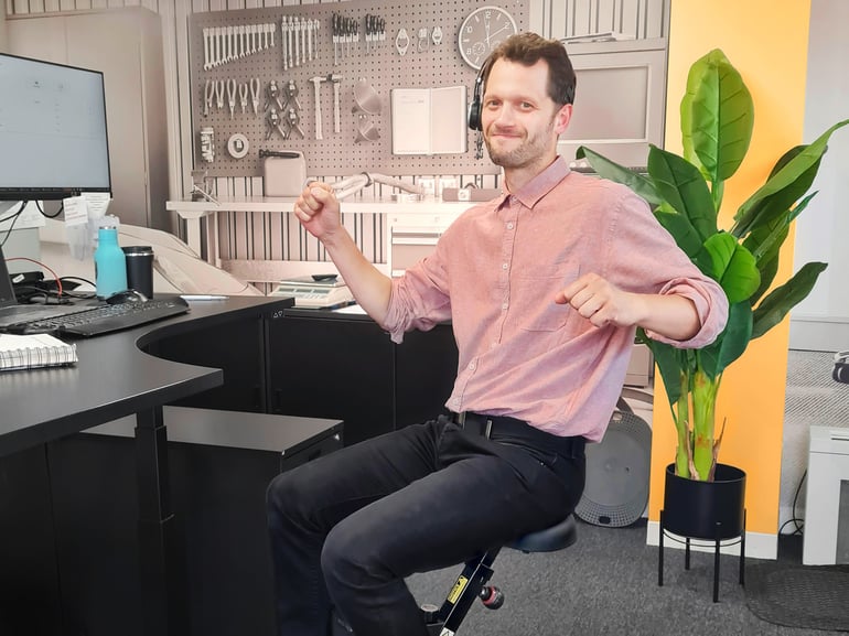 Ein Mann sitzt an einem Deskbike am Schreibtisch