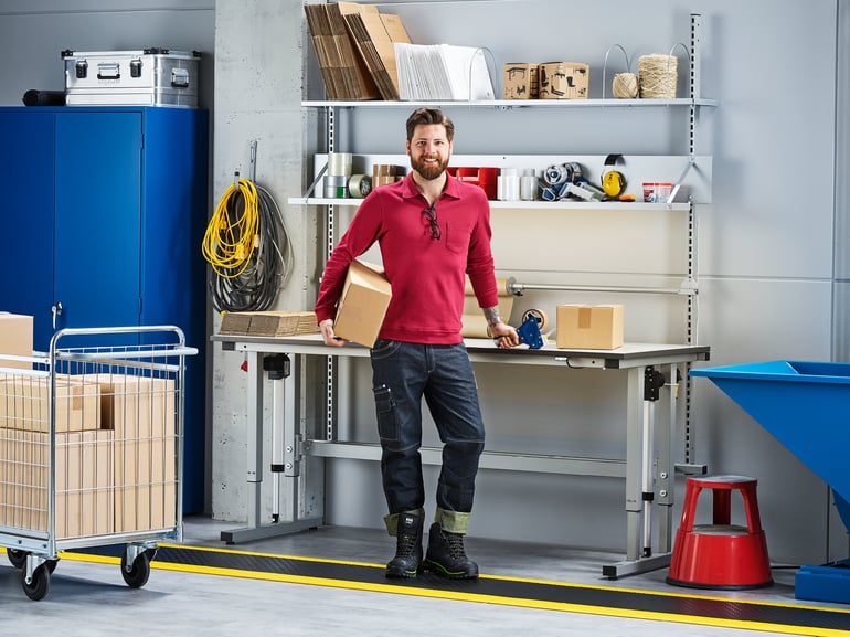 Man holding a box and staind in a warehouse