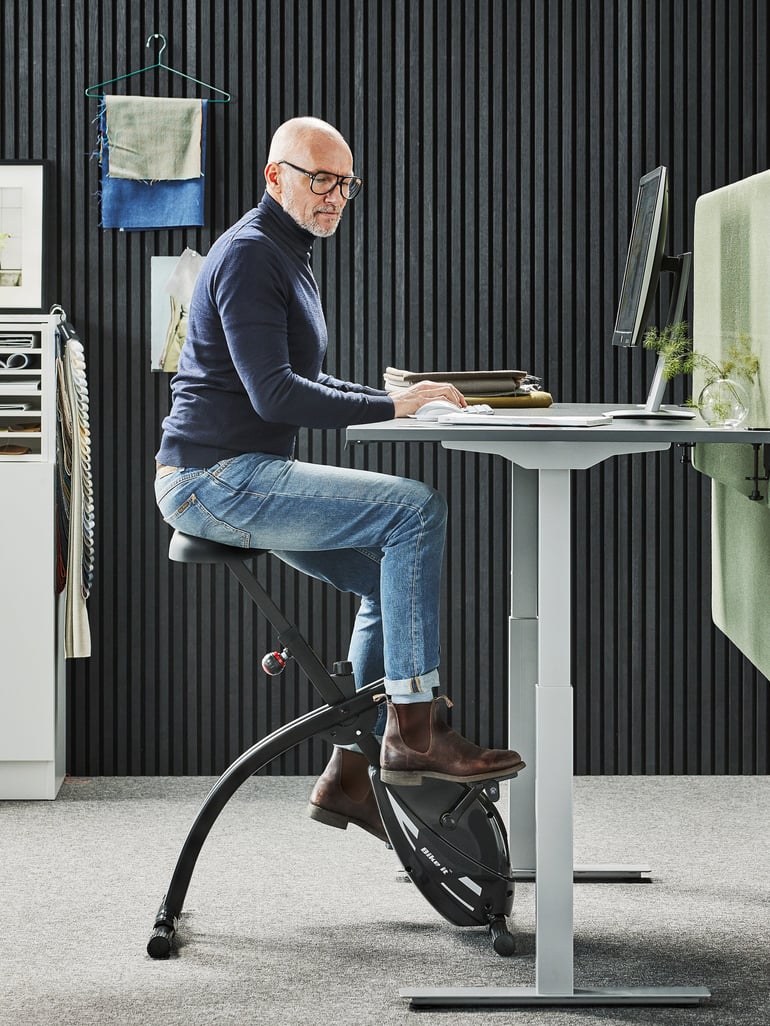 En person kører på kontorcykel ved sit skrivebord