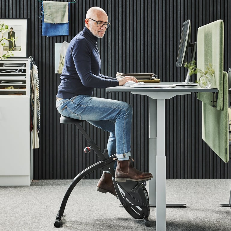office worker working on his computer while cycling on a desk bike