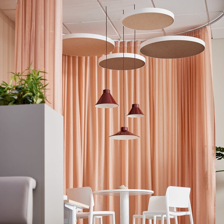 minimalist interior design featuring peach-colored curtains, a round white table with white chairs, and several round ceiling lights with dark red pendant lamps hanging from them