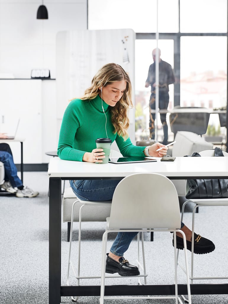 a young lady sitting at a desk focusing on a task in her tablet in a coworking space 